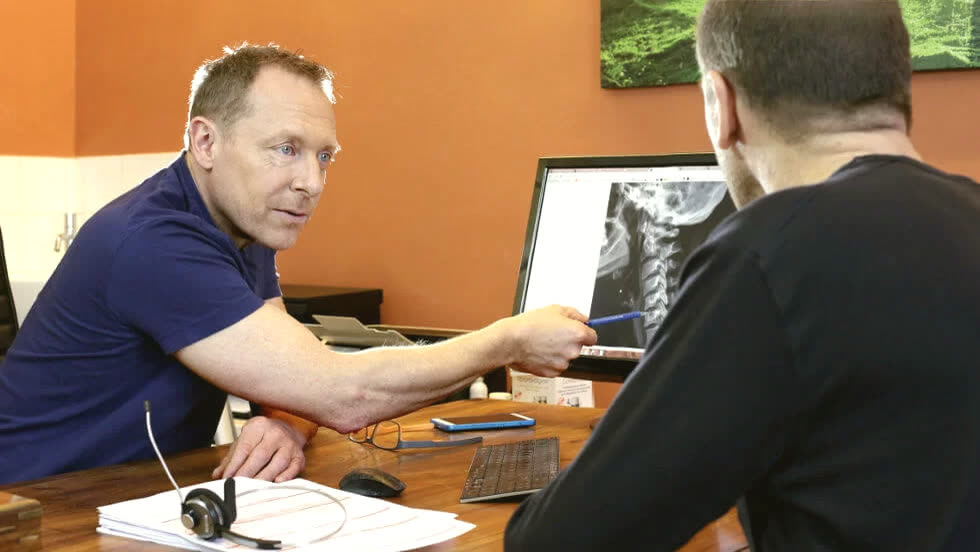 Marc Seguin montre à un patient sa radiographie des cervicales